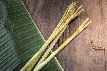 Fresh lemongrass stalks placed on a banana leaf over a rustic wooden table. A fragrant herb widely used in Indonesian cuisine, essential for enhancing the flavor of Eid dishes like rendang 