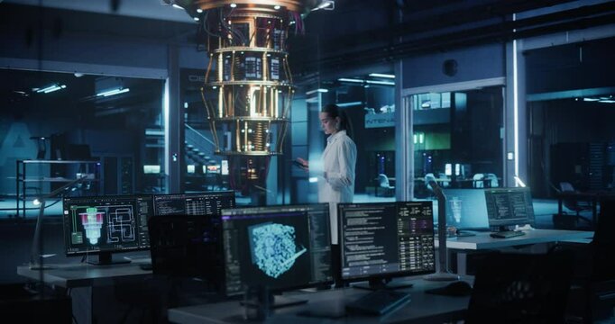 Female Computer Scientist Developing Quantum Machine Learning Algorithms, Using a Tablet Computer to Simulate and Test Hardware Performance. Engineer is Standing in Dark Office with Computer Displays