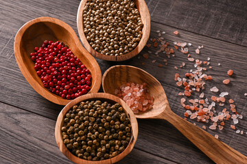 Colorful peppercorns and himalayan salt displayed in rustic wooden bowls and a wooden spoon, creating a warm and inviting culinary scene