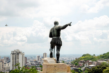 Fototapeta premium Statue of Sebastián de Belalcázar at the top of a viewpoint, with a panoramic view of the city of Cali, Colombia. He points with his right hand towards the horizon. In the background, 