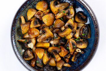 A close-up of sautéed mushrooms cooked with garlic and herbs, served in a rustic dish. A delicious and savory vegetarian side dish.