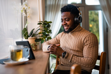 Freelancer using digital tablet to communicate online. He is sitting in bar and having video call.