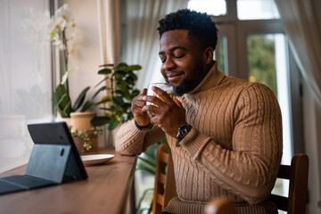 Young man using digital tablet to communicate online. He is sitting in bar,drinking tea and having video call.