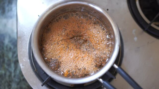 Making popular Indian beverage chai tea or masala chai in steel pot. 