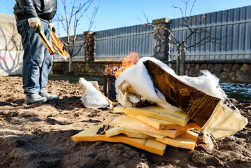 Man burning old sofa in bonfire in early spring.