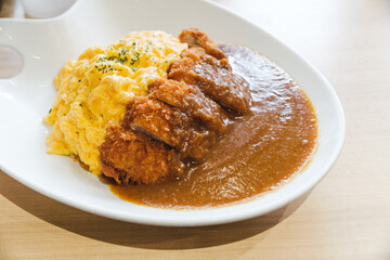 A delicious plate of Japanese katsu curry with crispy breaded pork cutlet, rich curry sauce, and fluffy scrambled eggs over rice. A popular comfort food in Japan, perfect for travelers and food lovers
