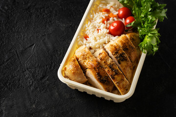 Lunch box with chicken, rice, vegetables, tomatoes, salad, fruits