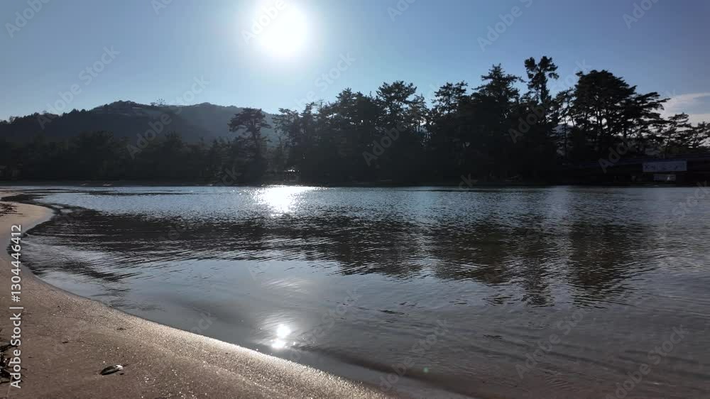 Poster sun reflecting on the calm waters of amanohashidate beach with trees and mountain in the background