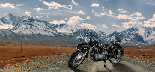 A black motorcycle is parked on a dirt road in front of a mountain range © Кристина Пахомова