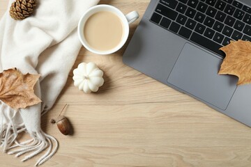 Workplace with autumn decorations, beige scarf, cup of coffee and laptop, top view 