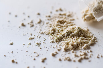 Opened probiotic capsule with powder scattered on white table surface, close-up macro shot, scientific and medical concept