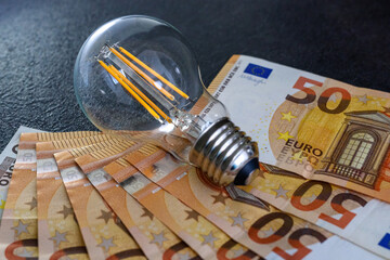 Expensive bills. Light bulb with banknotes indicate inflation and rising electricity bills....