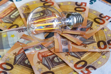 Expensive bills. Light bulb with banknotes indicate inflation and rising electricity bills. Increase in energy taxes.