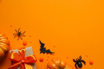 Halloween holiday decorations including gift box, pumpkins, spiders, bats on color background