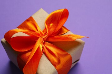 Top view photo of giftbox with orange satin ribbon bow on color background 