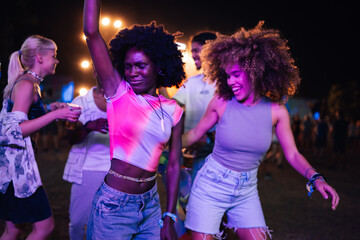 Young women dancing with friends at night music festival