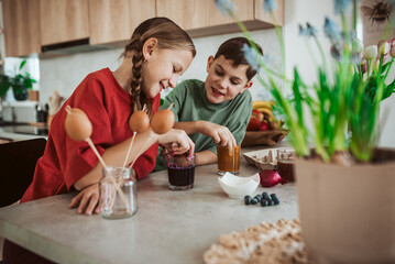 Siblings using natural dyes to decorate egshells for easter egg decorating.