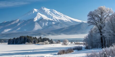 Snow-covered mountain looms over a frozen landscape under a clear blue sky wallpaper, background, texture detailed,   winter mountain landscape