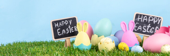 Easter tradition celebration, preparation for Easter egg hunting, invitation to children's morning party background. Colorful decor bunnies and Easter eggs in grass and blue background, copy space