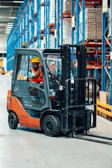Warehouse worker driving forklift in logistics center