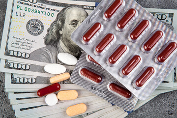 Pills and capsules on the background of the dollar. The concept of expensive medicine.