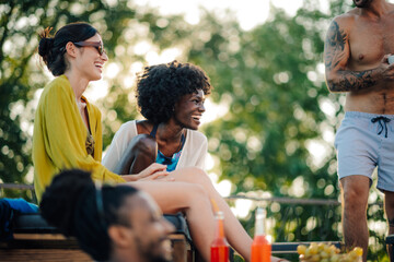 Friends enjoying drinks and laughing together at summer rooftop party