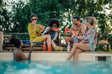 Friends eating watermelon by the poolside during summer vacation