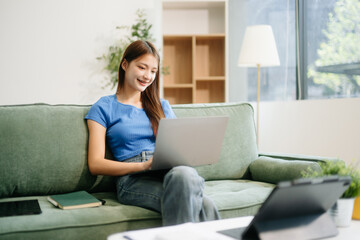 Obraz premium Young asian woman relax on comfortable couch at home texting messaging on smartphone and tablet smiling girl