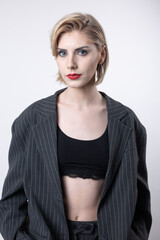 Fototapeta premium Portrait of a seductive, stylish business lady in the studio. Blonde girl in a suit and top.