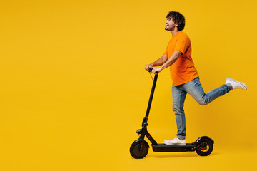 Side profile view young smiling fun happy Indian man he wear orange t-shirt casual clothes riding...