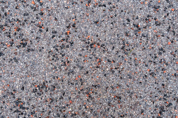 Granite chips remain scattered on asphalt sidewalk after ice melts, providing traction during...