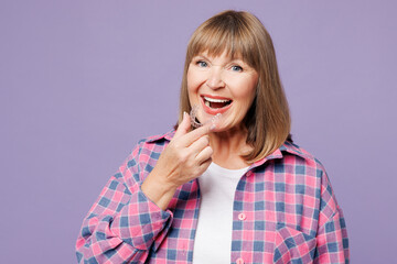 Elderly happy blonde woman 50s years old wear violet shirt casual clothes hold in hand invisible...