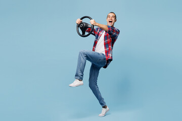 Full body side view young happy middle eastern man wear red shirt casual clothes hold steering wheel driving car isolated on plain pastel light blue cyan background studio portrait. Lifestyle concept.
