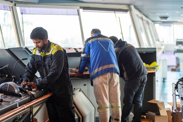 Fototapeta premium A marine engineer on the bridge of a large container ship, performing maintenance on navigation and communication equipment while the vessel is docked in port.
