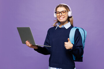 Young girl IT student wear blue casual clothes glasses headphones backpack bag hold use work on...