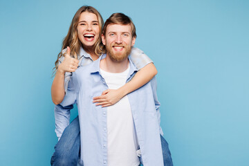 Fototapeta premium Young happy couple two friends family man woman wear shirt casual clothes together giving piggyback ride to joyful, sit on back isolated on pastel plain light blue background studio Lifestyle concept