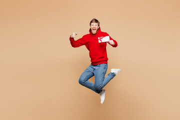 Full body young man he wear red hoodie casual clothes jump high hold point on gift certificate...