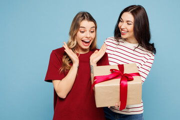 Young surprised fun couple two friends women wearing red casual clothes together hold present box...