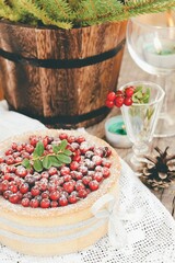 homemade cake with cranberries on a white tablecloth with candles and wine glasses