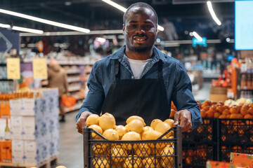 Fresh fruits. Grocery store worker in apron is near products