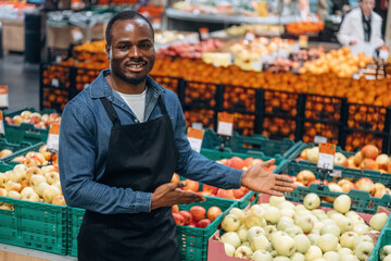 Tasty apples. Grocery store worker in apron is near products