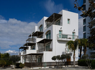 Modern white building surrounded by lush greenery under a bright blue sky in a peaceful neighborhood