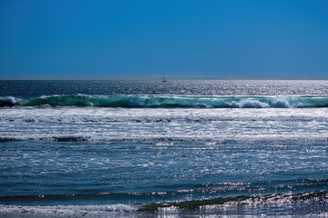 view of Pacific ocean from Huntington Beach; Waves moving towards shore; sailboat in the distance....
