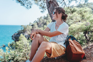 Beautiful young woman traveler is resting in the forest, enjoying the wild nature and landscape