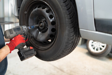 Loosening wheel nuts with an impact wrench in the car garage 