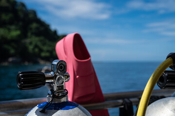 Diving equipment on a liveaboard. Airtank and pink fins in front of an island