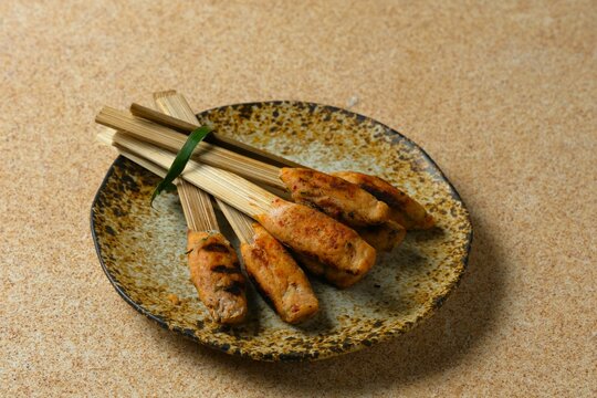 Sate lilit or sate pusut. Sate, originating from Lombok and Bali, Indonesia, is made from the basic ingredients of mashed chicken or beef, mixed with grated coconut and spices, grilled over charcoal.