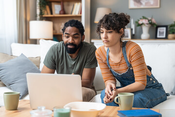 Relationship difficulties, communication problems. Young couple sitting at home having online...
