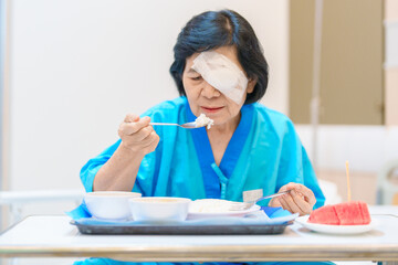Senior Woman eating food after eye surgery in hospital . Eye disease, Cataract,  Glaucoma, Age...