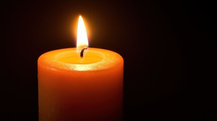 Bright Flame Dancing on an Orange Candle Against Dark Background
